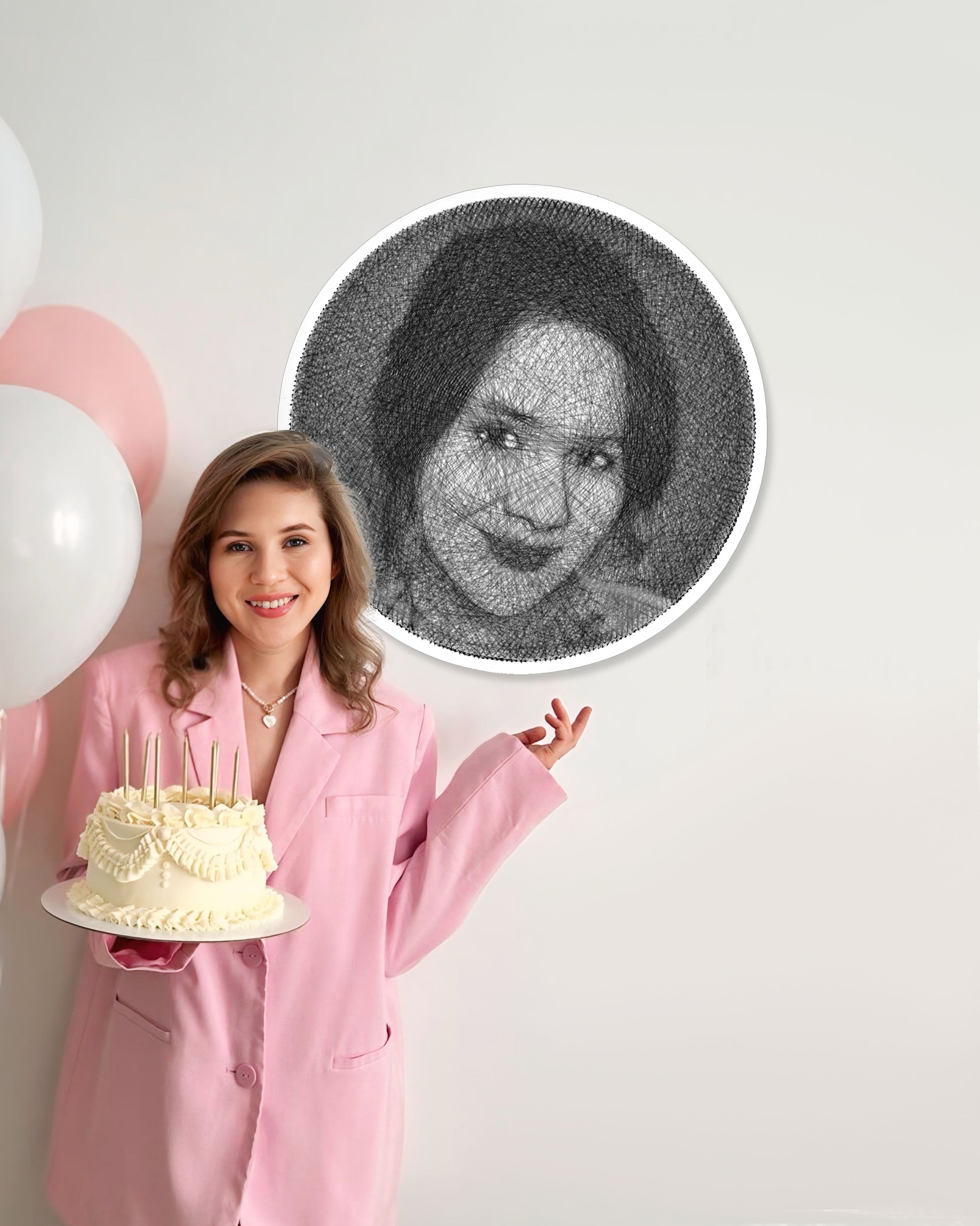 Woman in pink coat holding a cake next to a circular string art of a woman's face.